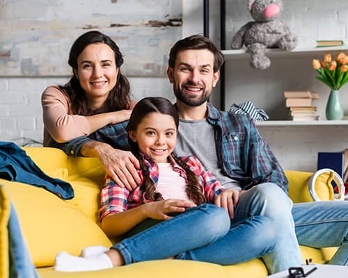 Happy Family Sitting on Couch in Their New Home in Massachusetts